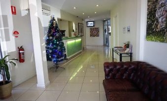 a hotel lobby with a christmas tree in the corner and a couch next to it at Jacksons Motor Inn