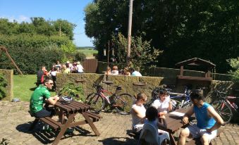 a group of people gathered around picnic tables in a park , enjoying their time together at The Farm Burscough