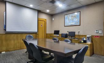 a conference room with a large table , chairs , and two computer monitors , as well as a projector screen and a whiteboard at Carlton Hotel