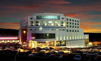 a large white building with a clock on the front is surrounded by other cars at Gold Country Casino Resort