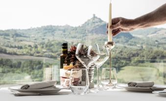 a person is lighting a candle next to a table with wine glasses and bottles at Albergo Posta Marcucci