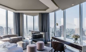a modern living room with large windows offering a view of the city , featuring comfortable seating and coffee tables at Icon Hotel
