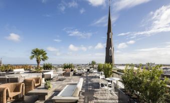 a rooftop patio with various seating options , including couches , chairs , and a dining table , as well as a large fountain in the at The Dewberry Charleston