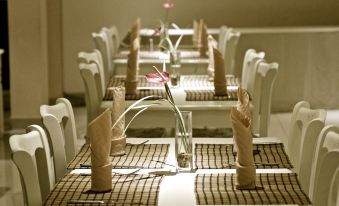 a dining room with tables set for a meal , each table has a vase of flowers placed on it at Star Hotel