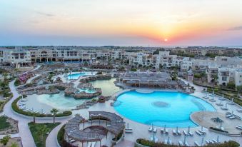 a large resort with multiple swimming pools and buildings , set against a beautiful sunset sky at Kempinski Hotel Soma Bay