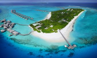 an aerial view of a tropical island with clear blue water and white sandy beaches , surrounded by lush green vegetation at Six Senses Laamu