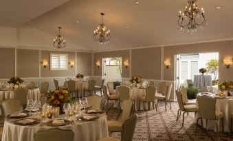 a well - decorated dining room with multiple tables and chairs arranged for a formal event , surrounded by elegant chandeliers at The Inn at Rancho Santa Fe