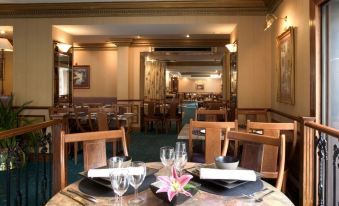 a dining room with a table set for two people , complete with plates , cups , and utensils at Berjaya Eden Park London Hotel