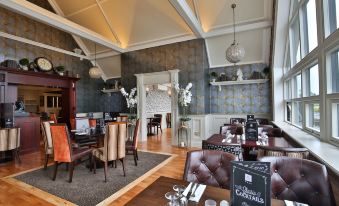 a modern restaurant interior with wooden floors , white walls , and a high ceiling , decorated with floral arrangements and elegant furniture at Clanard Court Hotel