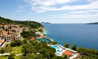 a beautiful coastal town with a large pool surrounded by buildings , trees , and a blue sea at Sun Gardens Dubrovnik