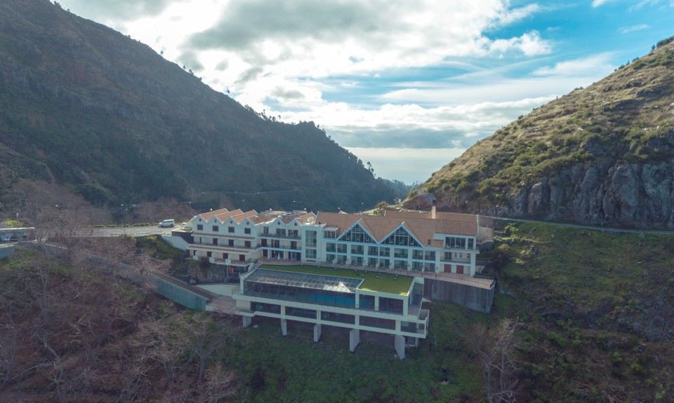 aerial view of a large building surrounded by mountains , with a pond in front of it at Eira do Serrado - Hotel & Spa
