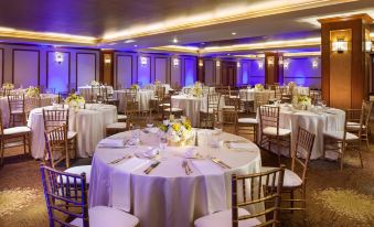 a well - decorated banquet hall with numerous tables set up for a formal event , including round tables covered in white tablecloths and chairs at The Westin Bonaventure Hotel & Suites, Los Angeles
