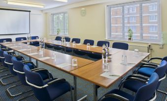 a large conference room with a long wooden table and several chairs arranged for a meeting at Holiday Inn Washington