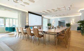 a conference room with a large table surrounded by chairs and a screen on the wall at Hob le Cheval Blanc