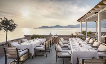an outdoor dining area with tables and chairs set up for a meal , overlooking the ocean at Aman Sveti Stefan