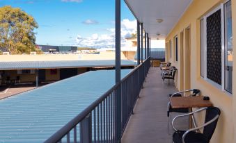 a balcony with chairs and tables , a railing , and a view of the ocean and mountains at Boulevard Lodge Bundaberg