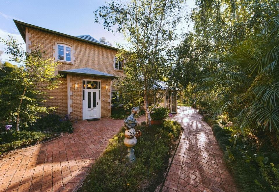 a brick house surrounded by trees and bushes , with a pathway leading to the front door at Holberry House