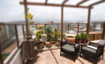 a balcony with a view of the city , featuring potted plants and a glass railing at Hotel Santa Maria