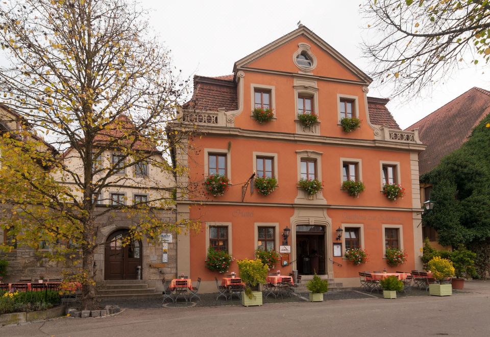 a large red brick building with a restaurant on the ground floor , surrounded by trees and benches at Akzent Hotel Schranne