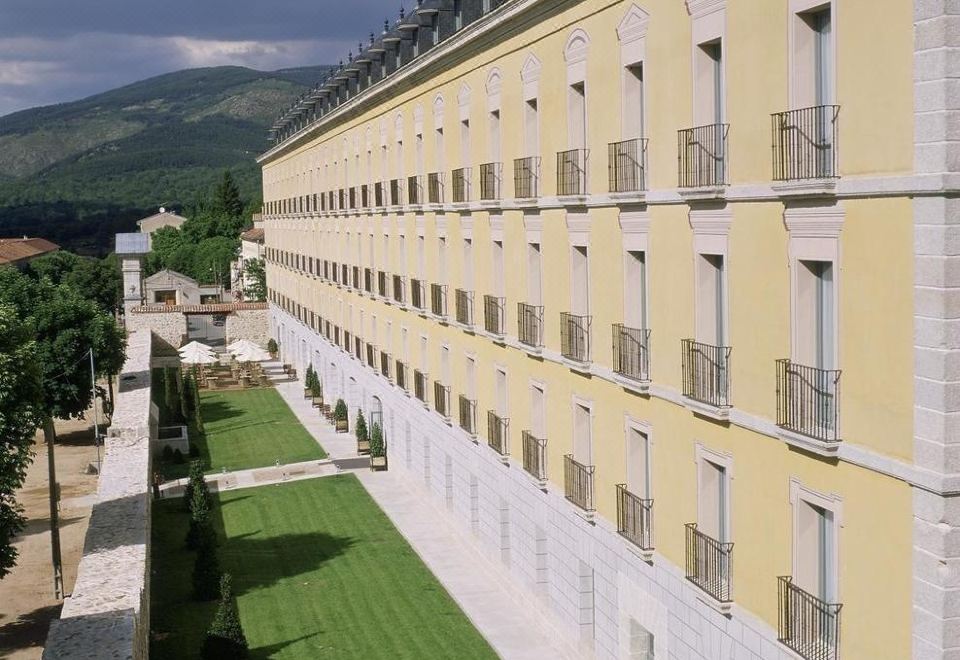 a large building with a long row of windows and balconies is surrounded by green grass at Parador de La Granja
