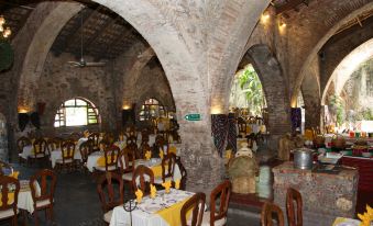 a large , well - lit restaurant with stone walls and arches , featuring several dining tables and chairs at Hotel Hacienda Vista Hermosa