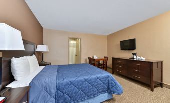 The bedroom is furnished with a large bed, desk, and chair, with the television positioned on top at Rodeway Inn Chicago