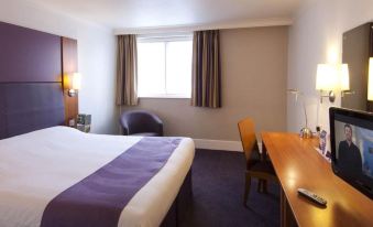 a hotel room with a bed , desk , and window , along with some other furnishings such as chairs and lamps at Premier Inn Whitehaven