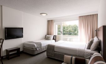 a hotel room with two beds , a tv , and a window overlooking a body of water at St Ives Apartments