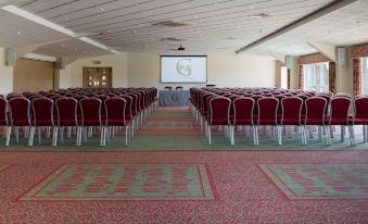 a large conference room with rows of chairs arranged in front of a projector screen at Greetham Valley