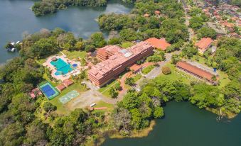 aerial view of a large building surrounded by trees and water , with a tennis court in the foreground at Melia Panama Canal