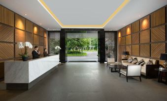 a modern hotel lobby with a reception desk , couches , and a large window looking out onto a garden at Delonix Hotel Karawang