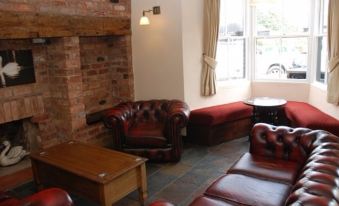a cozy living room with red leather couches and chairs , creating a warm and inviting atmosphere at The Swan Hotel