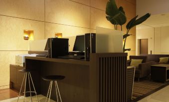 a modern office space with a reception desk and chairs , as well as a green plant at Mitsui Garden Hotel Okayama