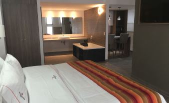 a hotel room with a king - sized bed and a bathroom with a sink and mirror at Hangar Inn Guadalajara Aeropuerto
