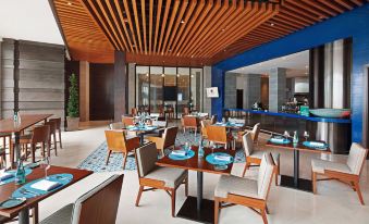 a restaurant with wooden tables and chairs , a bar , and blue lights in the ceiling at DoubleTree by Hilton Melaka