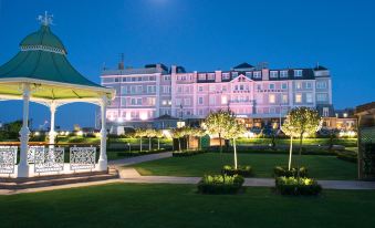 a large white building is lit up at night , with a gazebo in the foreground at Cbh Hythe Imperial Hotel Golf and Spa
