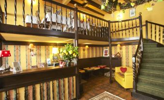 a cozy bar with wooden floors , a yellow couch , and a staircase leading to the second floor at Hotel Suisse