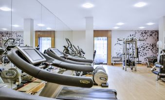a well - equipped gym with various exercise equipment , including treadmills and weight machines , arranged in rows at Sheraton Skyline Hotel London Heathrow