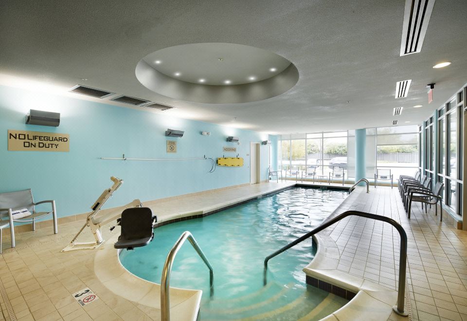 an indoor swimming pool surrounded by a modern building , with blue walls and a ceiling decorated with circular lights at SpringHill Suites Columbus OSU