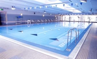 an empty swimming pool with blue water and white tiles , surrounded by lounge chairs and a ceiling with lights at Nagoya Tokyu Hotel