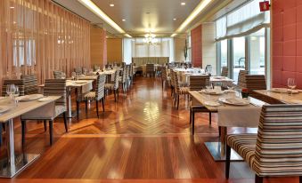 a large , well - lit dining room with wooden floors and tables set for a formal event at Unahotels Expo Fiera Milano