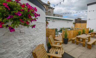 a wooden bench and table are situated in a courtyard with potted plants and a stone wall at New Inn Hotel
