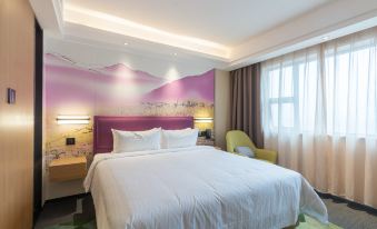 There is a bedroom with a large bed and a chair in the middle, accompanied by an art piece at Hampton by Hilton Ji'an