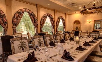 a long dining table is set with white tablecloths , napkins , and wine glasses in a restaurant at Mission Inn Resort & Club
