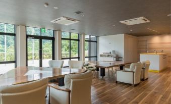 a large , modern office space with wooden floors and white walls , featuring several chairs and tables arranged in a comfortable seating area at Okuhita Onsen Umehibiki
