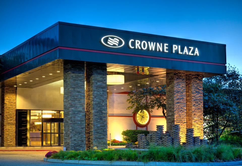 a large building with a crowne plaza sign on top of it , surrounded by trees at Crowne Plaza Suffern-Mahwah, an IHG Hotel