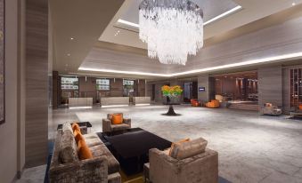 a spacious , well - lit hotel lobby with various seating options , including couches and chairs , as well as a large chandelier hanging from the at Sheraton Grand Bengaluru Whitefield Hotel & Convention Center