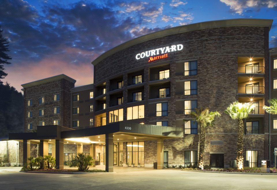 "a large , modern building with a curved facade and the word "" courtyard "" on it , set against a dark blue sky" at Courtyard Dallas Flower Mound