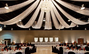 a large banquet hall with white draped curtains and a chandelier hanging from the ceiling at Holiday Inn Wilmington
