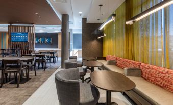 a modern restaurant with various seating options , including couches and chairs , as well as a dining area at SpringHill Suites Columbia